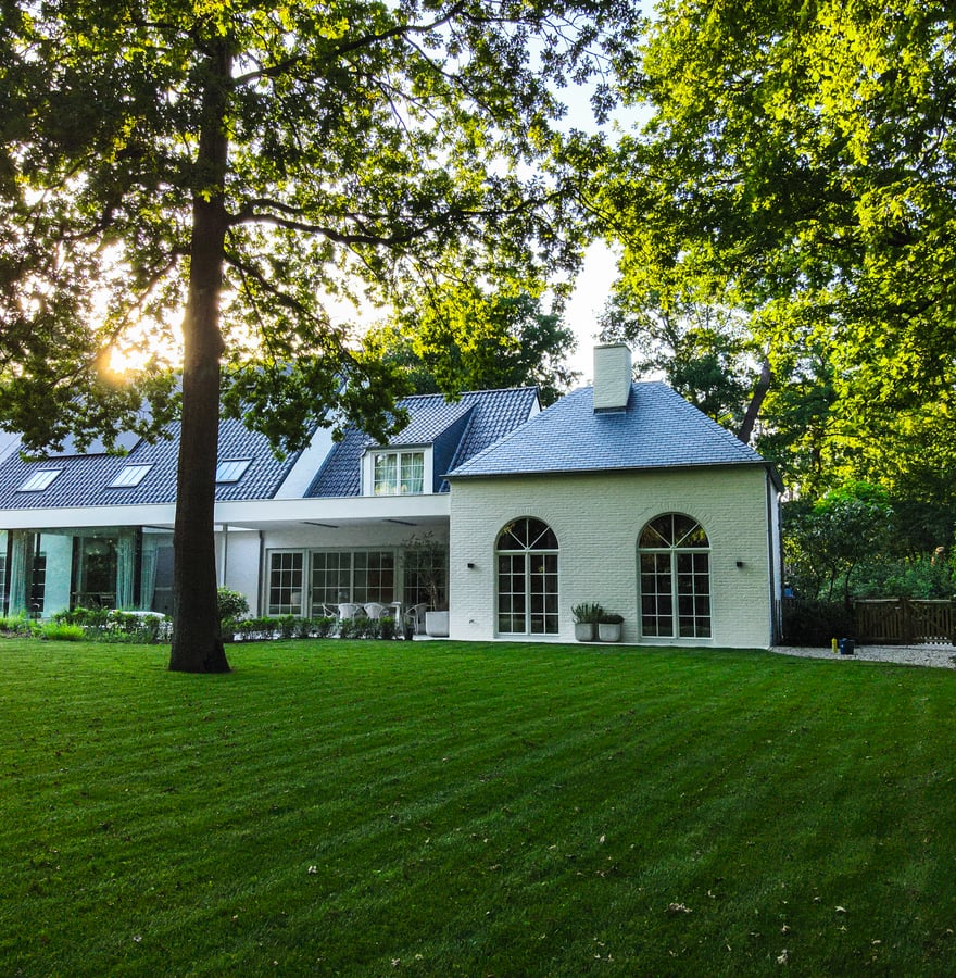 stijlvolle woning met grote tuin en avondzon door bomen
